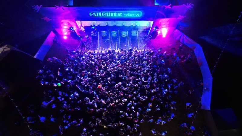 Foule d'un festival vue du ciel, scène éclairée en bleu et rose