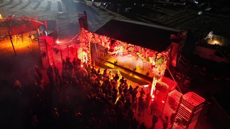 Scène de festival éclairée en rouge, la nuit
